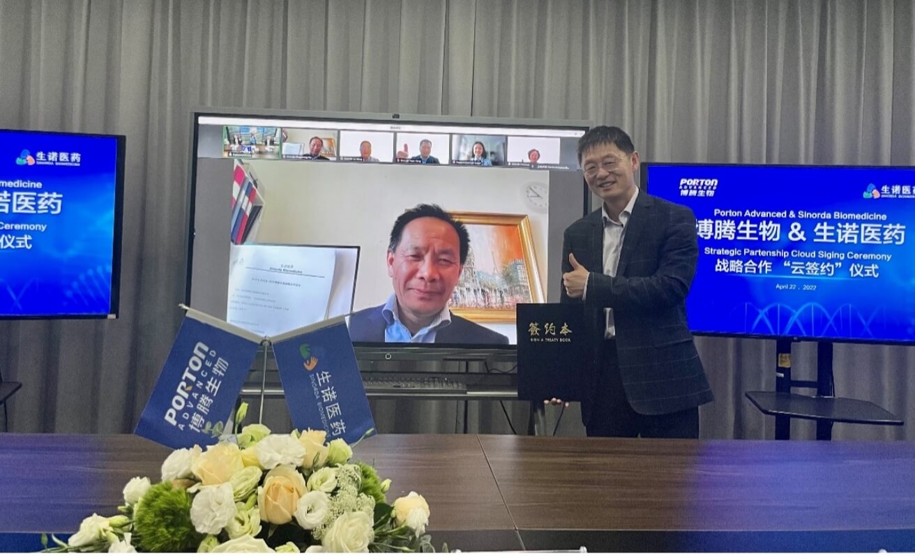 A man is standing in front of a table with two tvs in front of him.